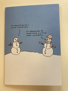 An image of two people made of snow, one wearing a rainbow-coloured hat and scarf. The other snow person is saying, "I'm dreaming of a white Christmas". The rainbow-coloured snow person is saying, "I'm dreaming of something a little more colourful".