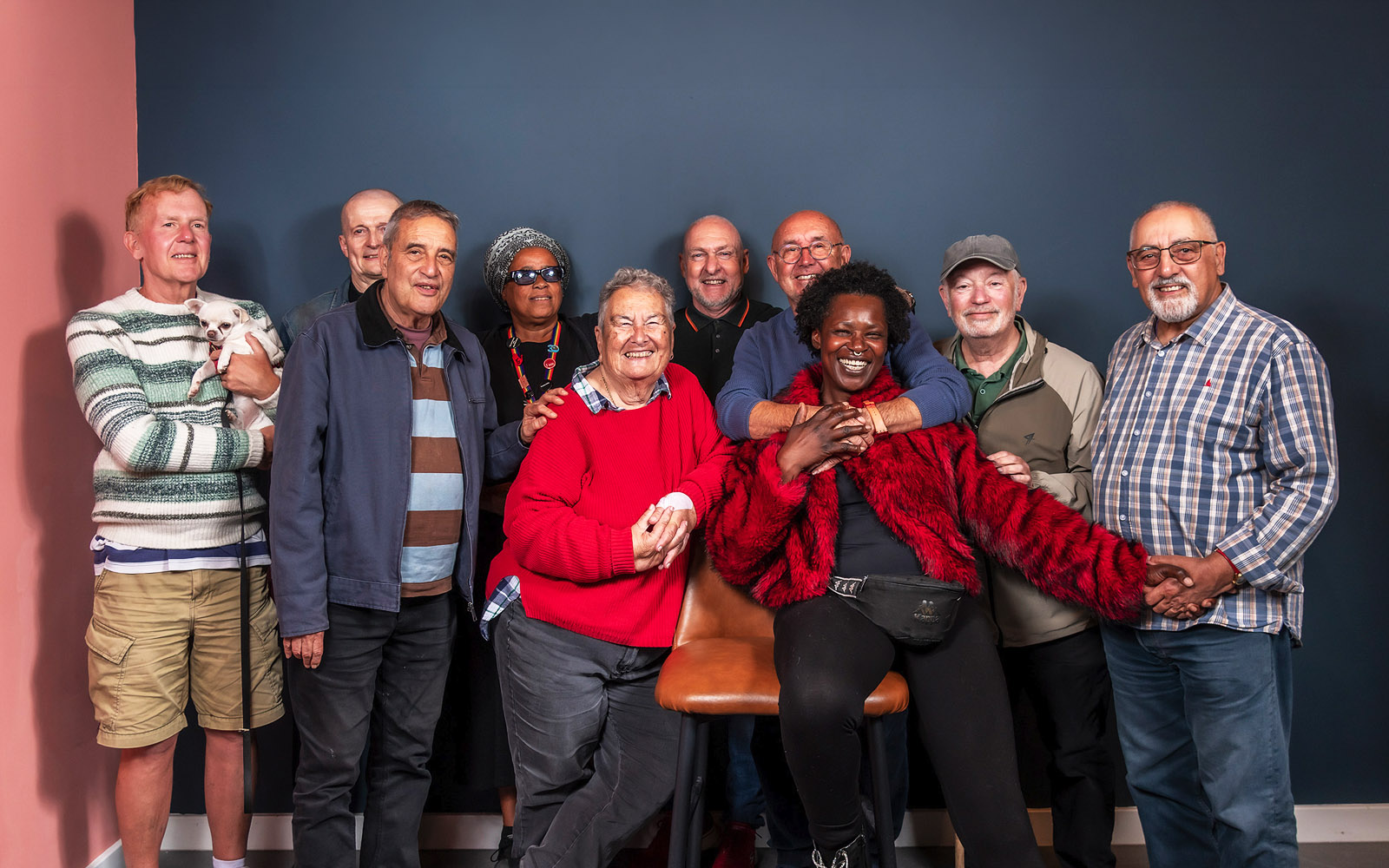 Group portrait of older LGBTQ+ community members and allies smiling together, including one person holding a small dog. The photo represents BOLD’s community connection and support for older LGBTQ+ people.