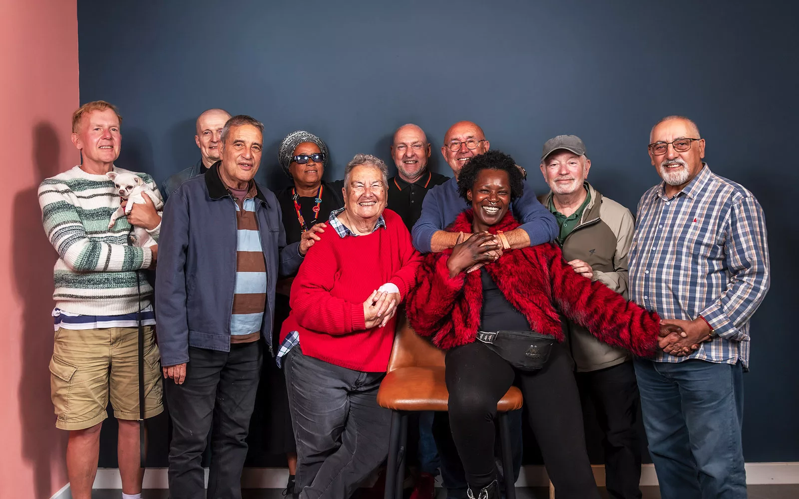 Group portrait of older LGBTQ+ community members and allies smiling together, including one person holding a small dog. The photo represents BOLD’s community connection and support for older LGBTQ+ people.